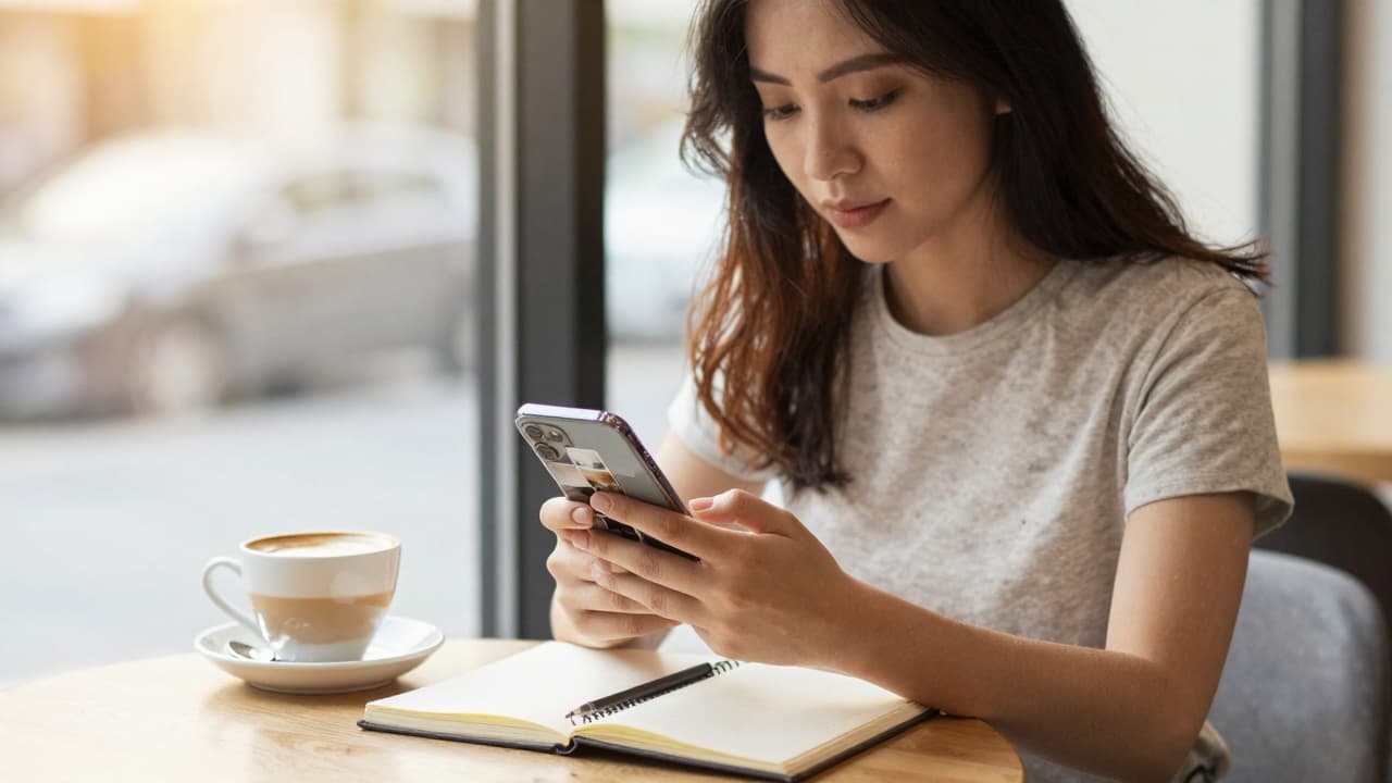 A creator checking the Instagram AI content policy 2026 labeling rules on a phone, with the AI info label visible on a post and a compliance notebook on the desk