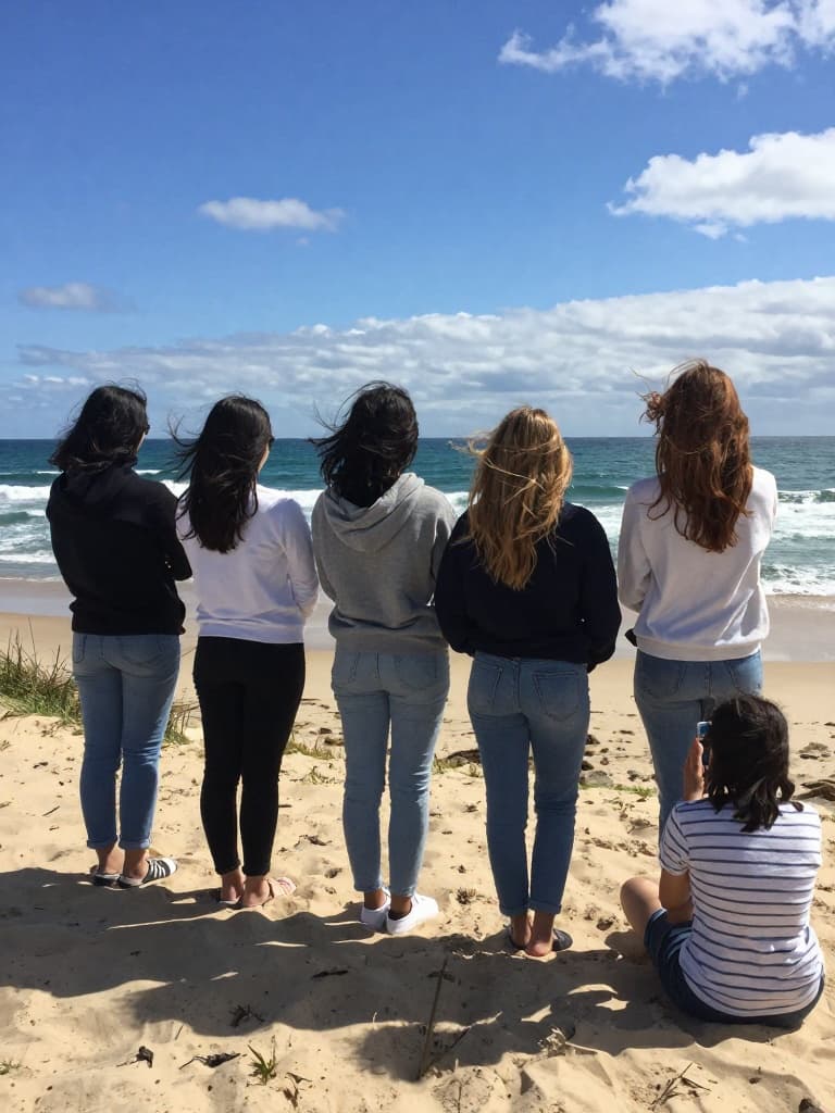 Smartphone photo of a group of young women from behind, standing and…