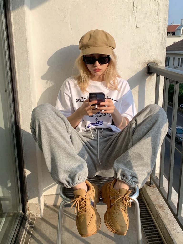 Smartphone photo taken outdoors on a balcony, of a young blonde woman…