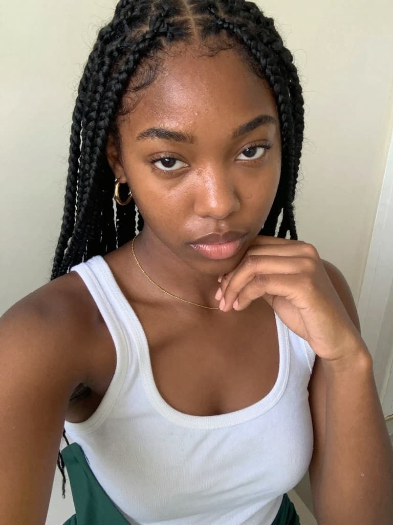 Smartphone selfie of a young Black woman with long black box braids…