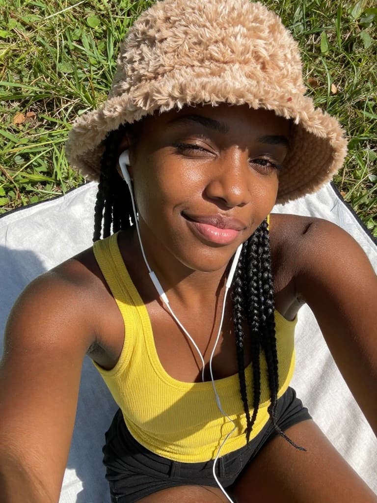Smartphone selfie of a young Black woman with natural, textured skin…
