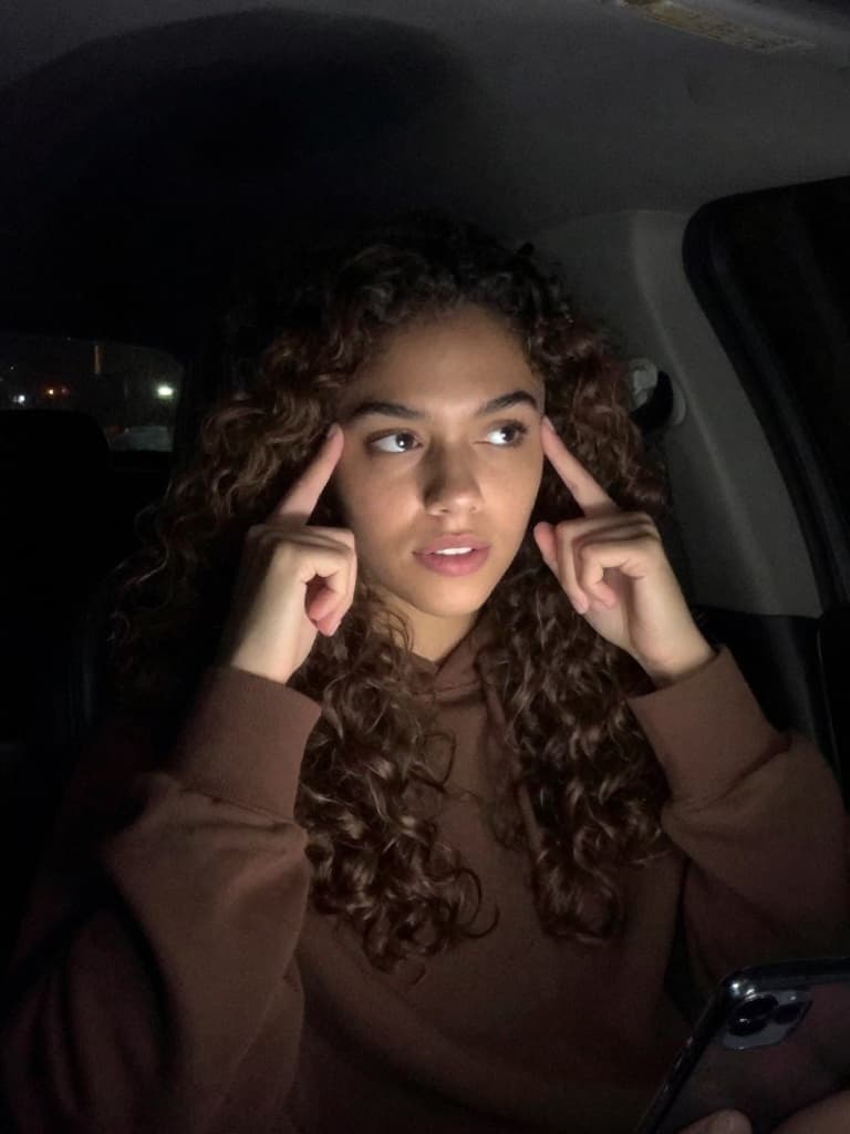 Video still from a smartphone, taken inside a car at night. A…