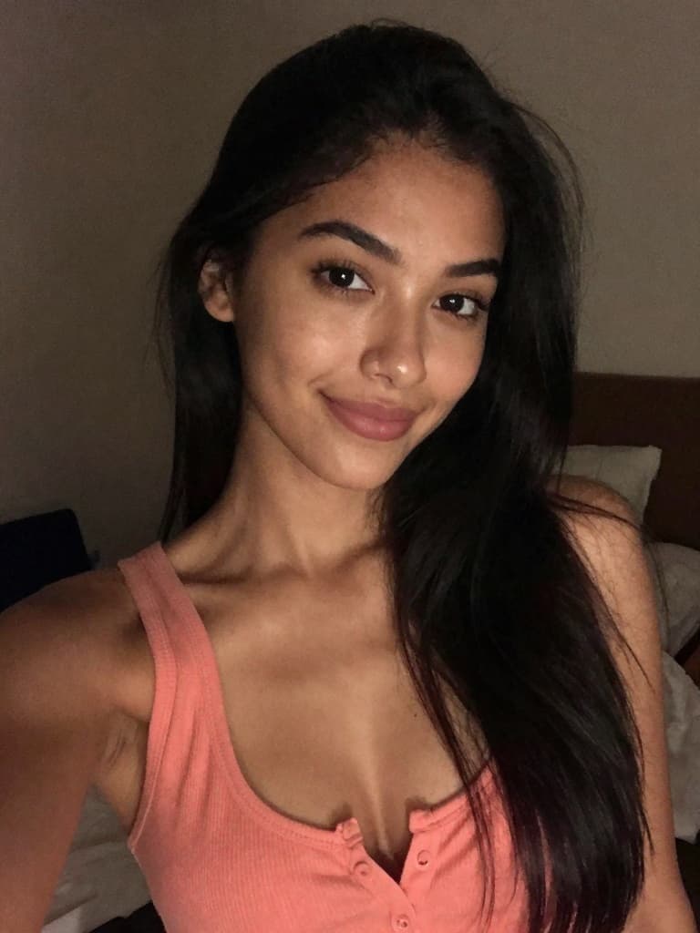 High-ISO smartphone selfie of a conventionally attractive young…